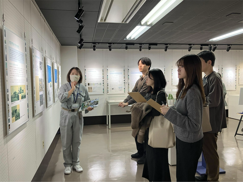 「国登録有形文化財 濱家住宅西洋館のあゆみ」企画展で職員から説明を受けている様子